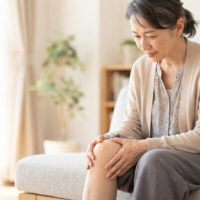 膝の張りを気にして膝に手を添える女性のイメージ