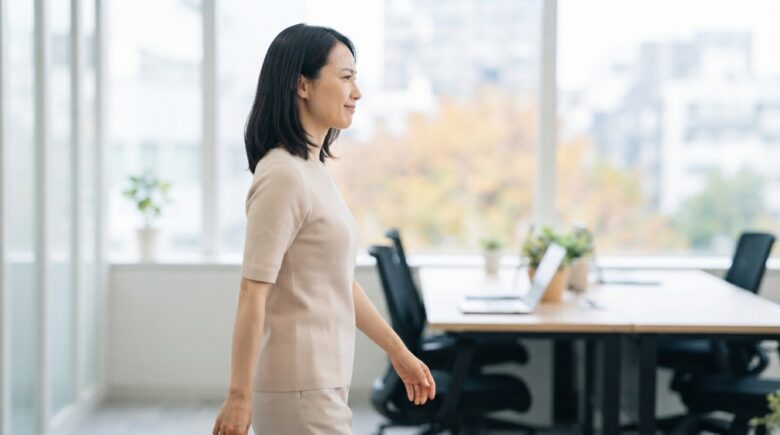 デスクワークの合間に席を立ち、オフィスの中を歩く女性